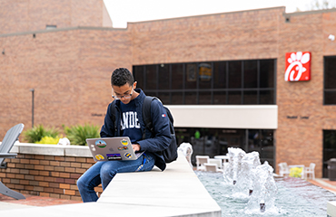 student in plaza with laptop